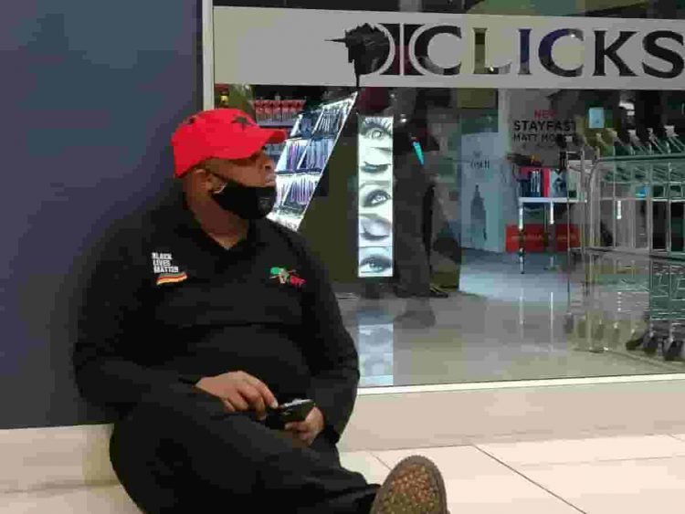 clicks - a man seated in front of a store